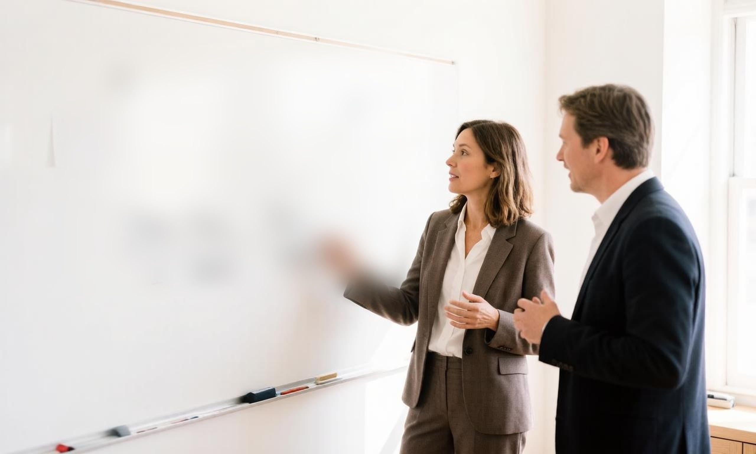 Two business partners reviewing a five-stage growth roadmap sketched on a whiteboard